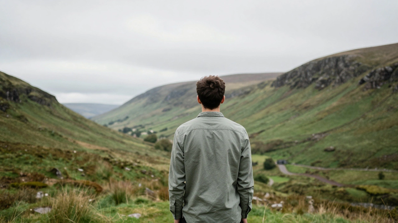 A person wearing a sage green shirt standing amidst the lush green mountains of Wicklow.